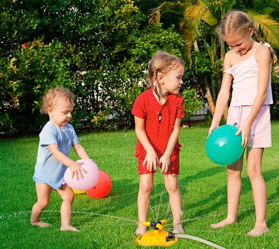 Niñas juegan en un jardin con bombas llenas de agua