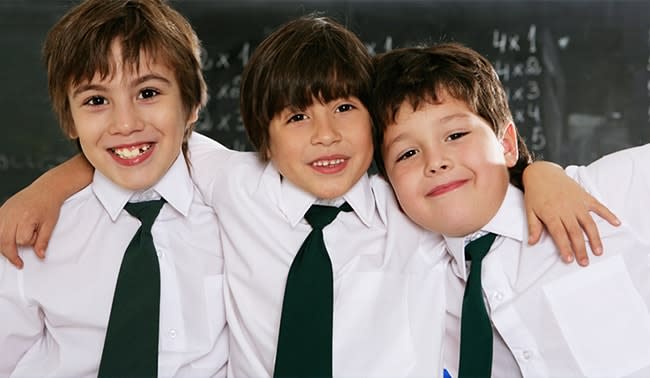 Tres amigos jovenes con camisas blancas y corbata verde sonrien
