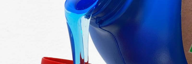 Detergente líquido que fluye del vaso a una tapa