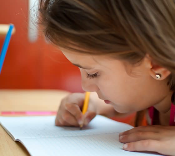 Niña escribe en un cuaderno con un lapiz