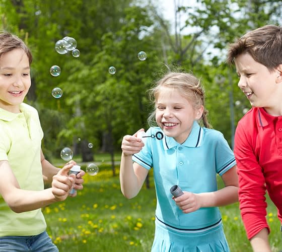 Niños jugando a hacer burbujas de jabon en un parque