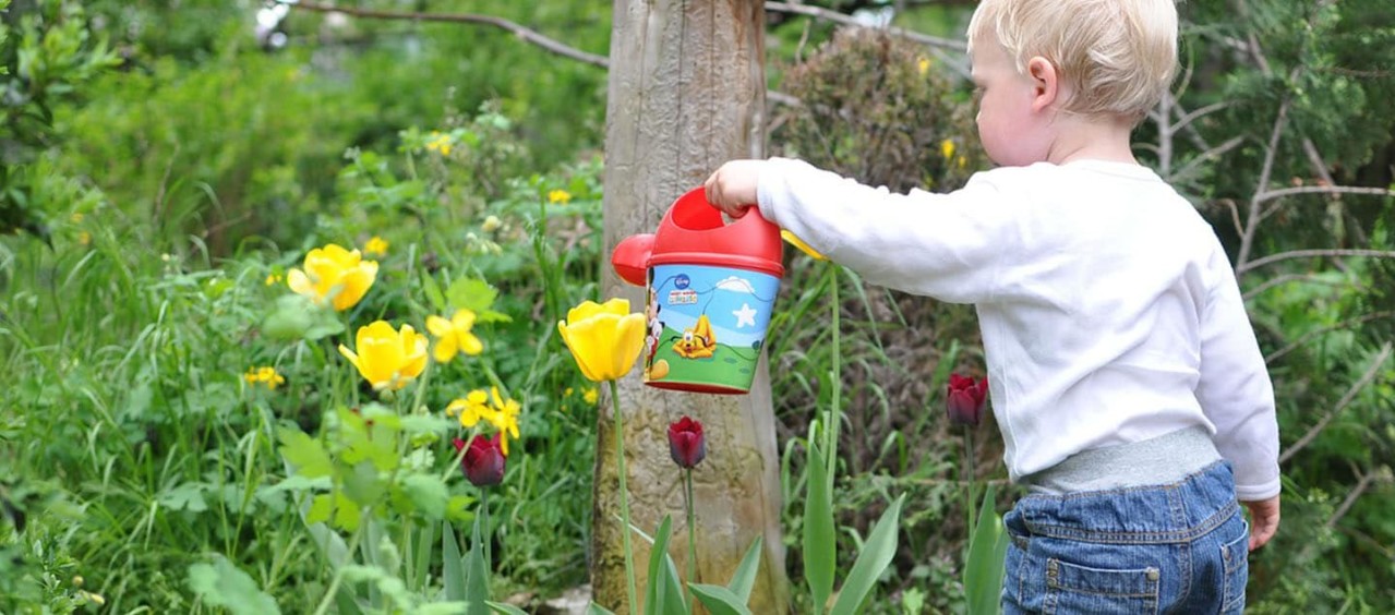 Niño regando las flores del jardin